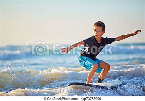 Skilled Teenager Riding Surfboard And Balancing A Long Wavy Sea