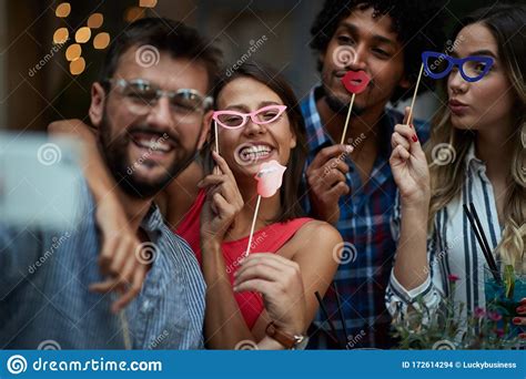 Four Young Multiethnic Adults Having Fun With Props On Sticks Fun Joy Crazy Party Friends