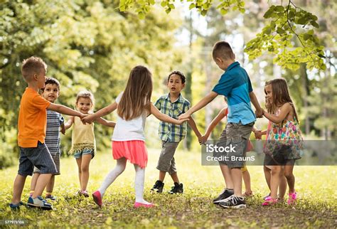 Group Of Small Kids Playing Ringaroundtherosy In The Park Stock Photo