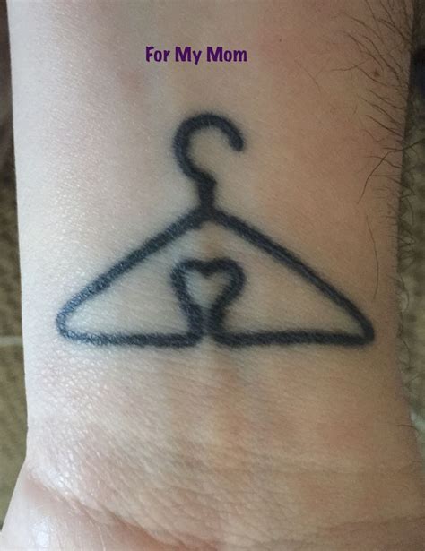 A Hand With A Tattoo On It That Has A Hanger In The Shape Of A Heart