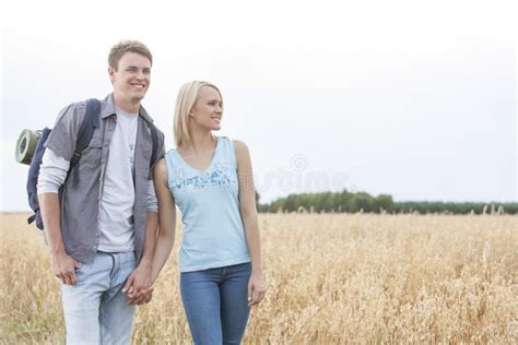 Young Hiking Couple Holding Hands While Standing On Field Stock Image
