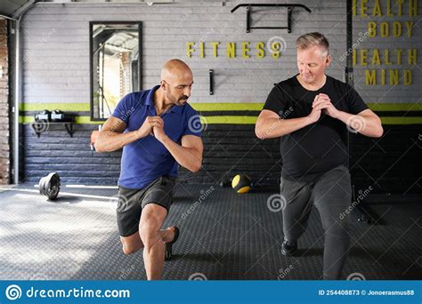 Personal Trainer Instructing Senior Man Leg Lunges Exercise Stock