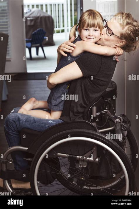 A Paraplegic Mother Holding Her Daughter On Her Lap In Her Wheelchair