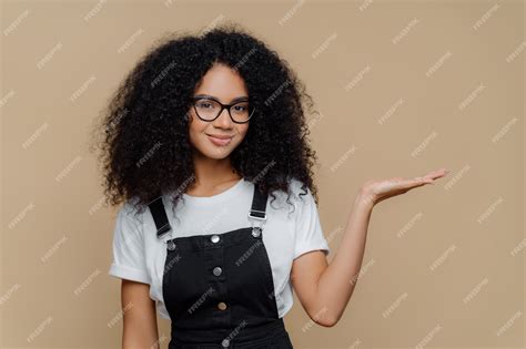 Premium Photo Curly Girl Raises Palm Holds Empty Space Wears