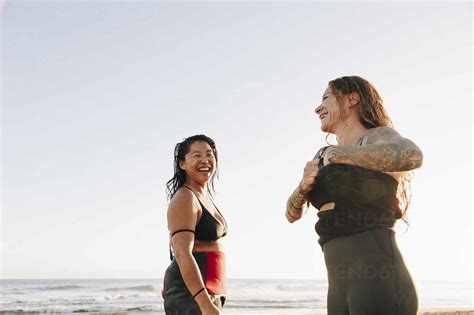 Happy Female Surfers Talking To Each Other Undressing At Beach Stock Photo