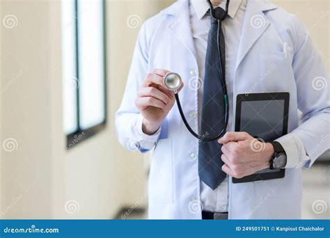 Doctor Holding Stethoscope at Hospital. Friendly Male Doctor Dressed in
