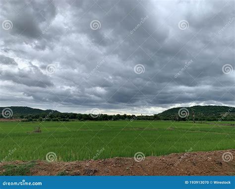 Beautiful Scenery Of A Green Field Surrounded By Mountains Under Dark