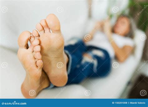 Bare Feet Of Woman In Jeans Using Smart Phonebare Foot Stock Photo