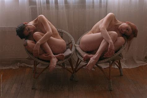 Two Naked Girls Artistically Sit On The Chairs In The Room Symmetrically By Stocksy