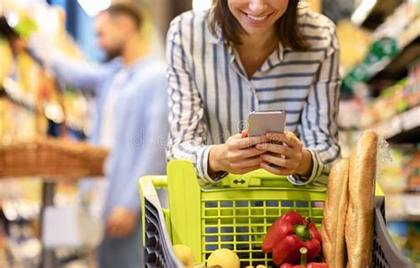 Young Woman With Mobile Phone Shopping In Hypermarket Stock Image