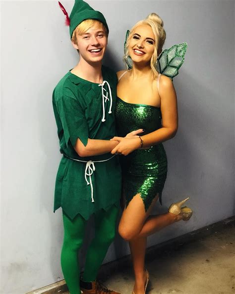 Two People Dressed As Tinkerbells Posing For A Photo In Front Of A Wall