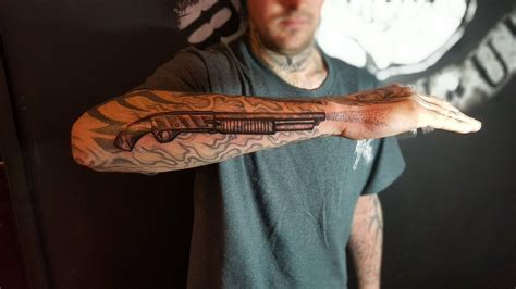 A Man With A Tattoo On His Arm And Arms Is Holding Something In One Hand