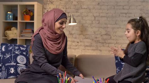 Young Muslim Mother In A Hijab Takes A Book In Her Hands Her Daughter