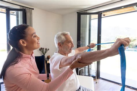 Biracial Female Physiotherapist Helping Senior Man To Exercise With Resistance Bands Stock Image