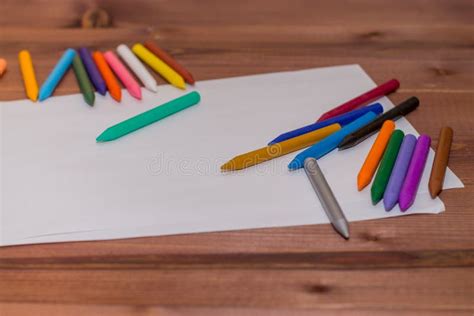 Colorful Crayons With A White Blank Sheet Of Paper On A Wooden B Stock