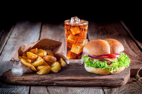 Burger With Fries And Cold Drink On Old Wooden Board Stock Photo