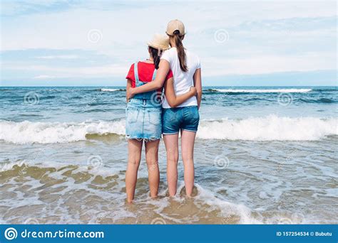 Two Girl Friends On The Sea Shore Hugging Each Other Stock Photo