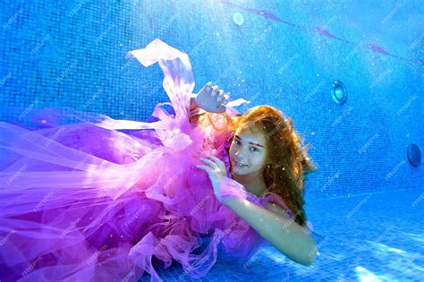 Милая девушка позирует под водой в красивом платье на дне открытого