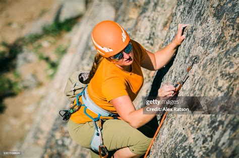 A Female Rock Climber Lead Climbs A Demanding Rock Face With Small Hand