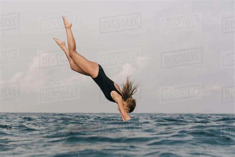 Side View Of Woman Diving Into Sea Against Sky Stock Photo Dissolve