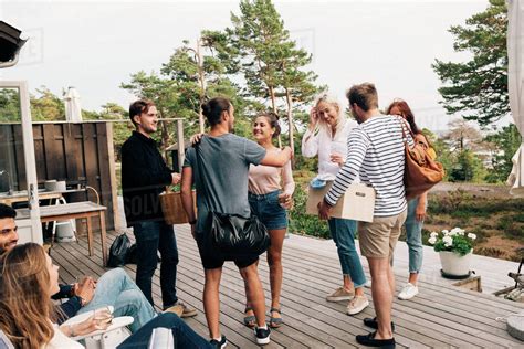 Happy friends greeting each other on cottage deck - Stock Photo - Dissolve