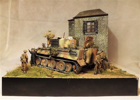 A Toy Tank With Soldiers Standing Next To It In Front Of A Small Brick