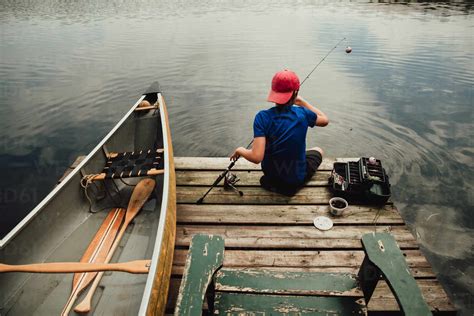 Teen Boy Fishing From A Dock On A Lake With Tackle Box In The Summer