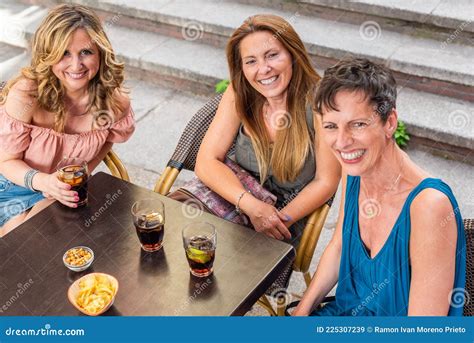 Adult Women In A Cafe Laughing And Having Drinks While Looking At