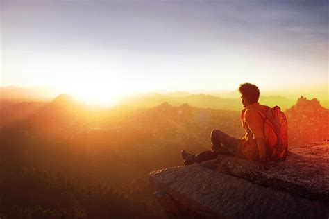 Man Sitting on Edge Facing Sunset · Free Stock Photo
