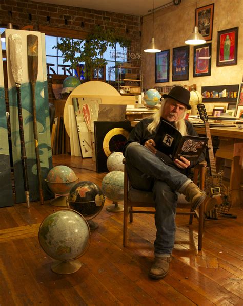 A Man Sitting On A Chair In A Room With Lots Of Globes Around Him