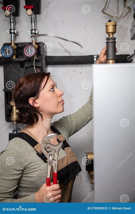 Female Plumber With A Pellet Heating System In The Basement Stock Image