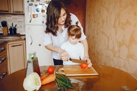 Mamá Junto Con Su Hija Cocina Verduras En Casa En La Cocina Foto Gratis