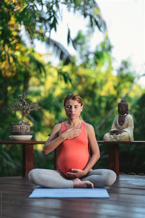 pregnant woman doing yoga meditation by stocksy contributor alexander grabchilev stocksy