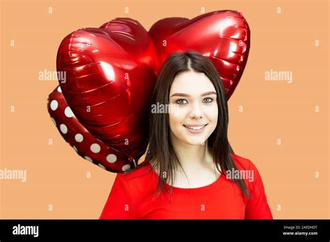 A Brunette Girl In Red Dress Holds Over Her Head Three Red Heart Shaped