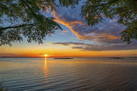 Colorful Sunset Over Lake Sun Hiding In Water Blue Cloudy Sky With
