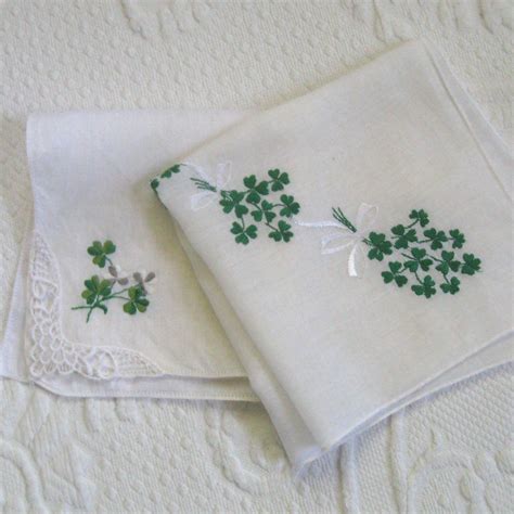 Two White Napkins With Green Clover Embroidered On Them