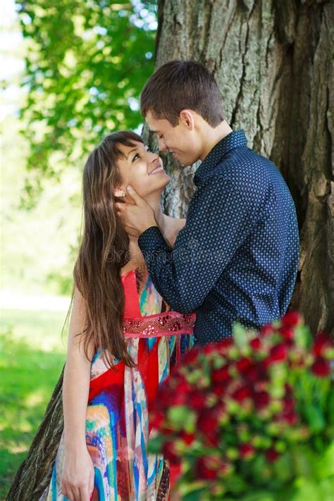 Young Guy Affectionately Hugs Girl In A Sunny Nature Stock Photo