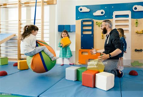 Preschool Teacher And Happy Children Playing In Gym Room In