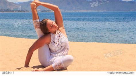 Girl In White Lace Costume Shows Yoga Asana Leg Behind Head On Beach