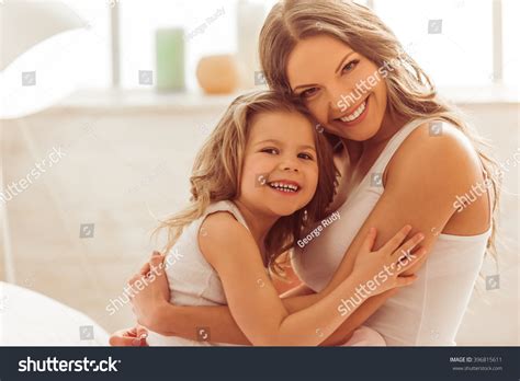 Beautiful Young Mom And Her Little Daughter Are Cuddling Looking At Camera And Smiling While