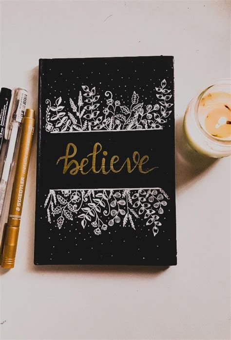 A Notebook With The Word Believe Written On It Next To Some Pens And A