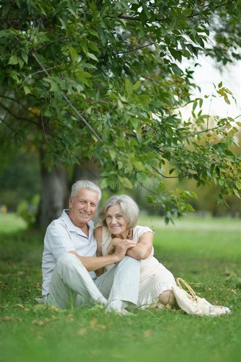 Portrait Of Beautiful Senior Couple Sitting On Grass Stock Photo