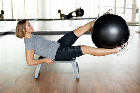 A Young Woman Does Abs Exercises In The Gym On A Bench Using A Fitball The Concept Of Sports