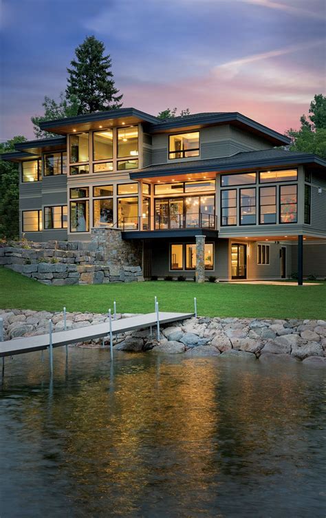 A Large House Sitting On Top Of A Lush Green Hillside Next To A Lake At