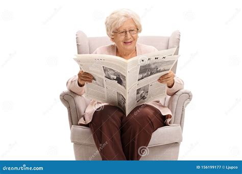 Senior Lady Sitting In An Armchair And Reading A Newspaper Stock Image