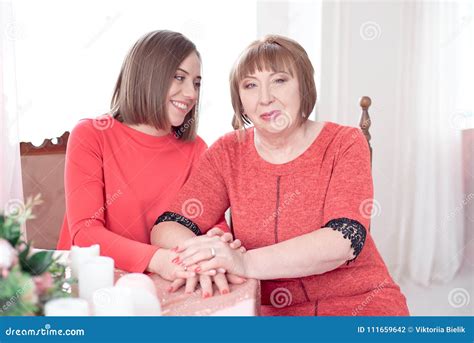 Mature Mother And Daughter Holding Hands Siting At The Table Stock