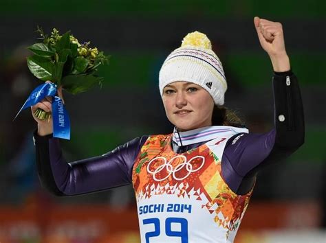 A Woman Holding Flowers And A Medal In Her Hand While Wearing A Ski
