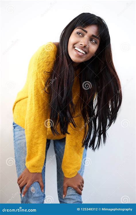 Attractive Young Indian Woman Smiling With Hands On Knee Against White