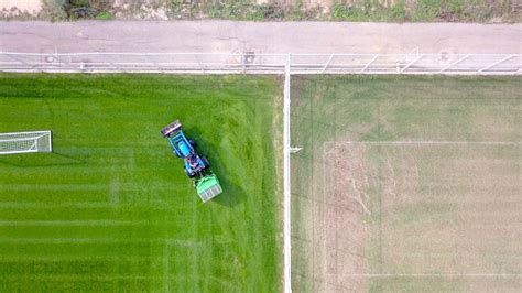 Large Lawn Mower Cutting Green Grass In A Soccer Field Stock Photo