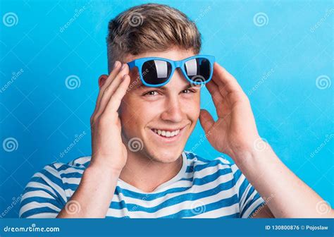 Portrait Of A Young Man Holding Sunglasses On His Forehead In A Studio
